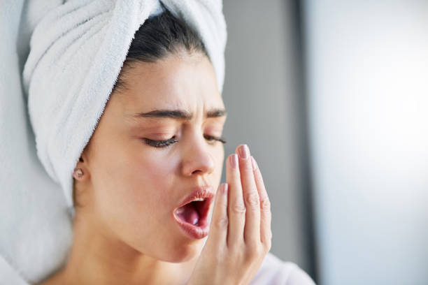 Check up on your oral hygiene Shot of a beautiful young woman checking her breath at home woman wrapped in bath towel stock pictures, royalty-free photos & images