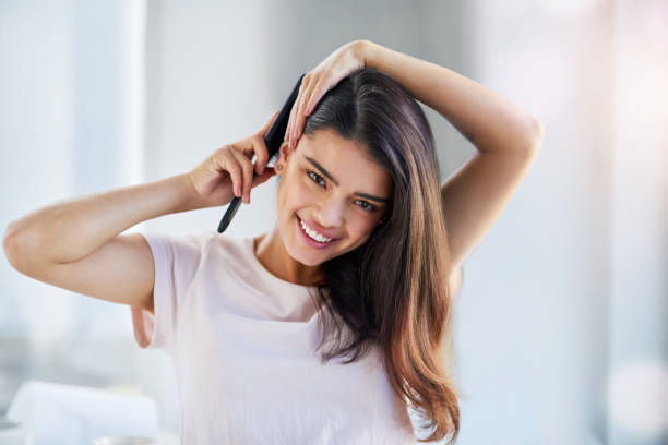 Step-by-Step Guide: Applying Pre Bonded Remy Hair Extensions at Home 2 Care for your crown Portrait of a beautiful young woman brushing her hair in the bathroom at home Section Your Hair stock pictures, royalty-free photos & images