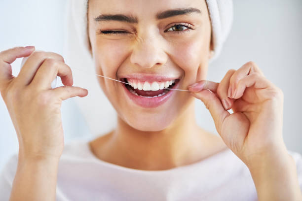 Go the extra mile for your smile Portrait of a beautiful young woman flossing her teeth in the bathroom at home woman wrapped in bath towel stock pictures, royalty-free photos & images