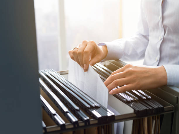 Office clerk searching files in the filing cabinet Professional female office clerk searching files and paperwork in the filing cabinet secretary stock pictures, royalty-free photos & images