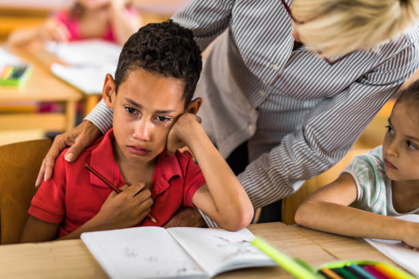 istock African American elementary student crying on a class while his teacher is consoling him. 1131975948
