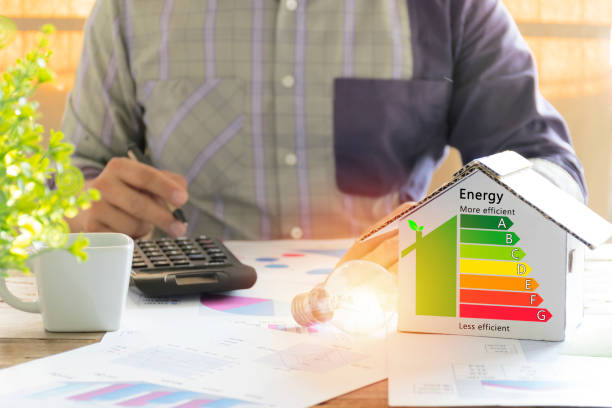 Men who are calculating cost savings from energy. Hand holding a pen. Men who are calculating cost savings from energy. Hand holding a pen. Detail of house efficiency rating on digital tablet screen. Concept of ecological and bio energetic house. Energy class. fuel and power generation stock pictures, royalty-free photos & images