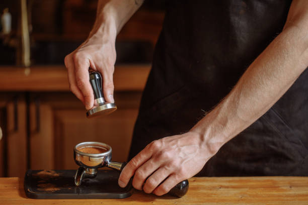 barista utilise un pilon pour appuyer sur les seads de café - tamping photos et images de collection