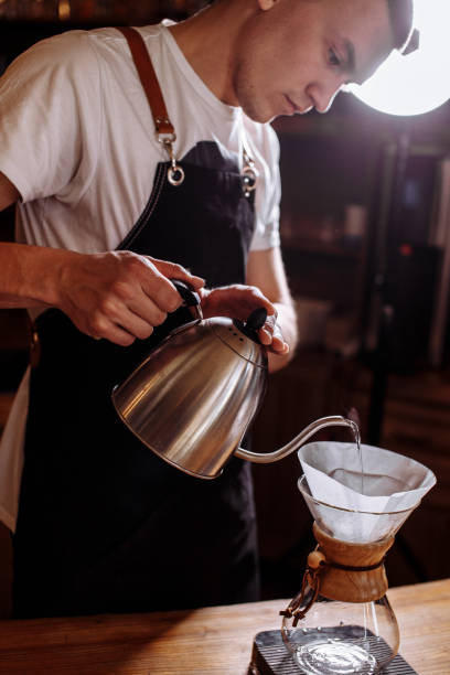male is adding hot water to coffee