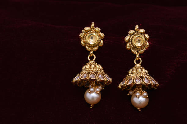 istock Fancy Designer golden earrings closeup macro image on red background 1131981357