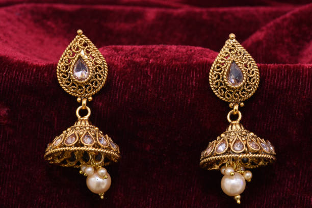 istock Fancy Designer golden earrings closeup macro image on red background 1131985480