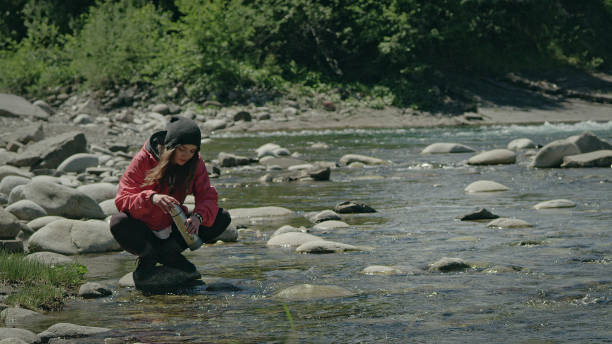 istock Hiking in mountains. Woman getting water into thermos 1131985698