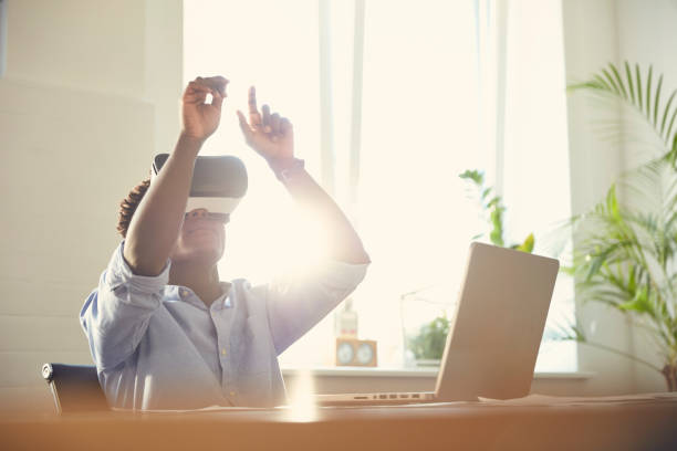 istock Young frican ethnicity man using virtual reality glasses at office. Touching big imaginary object 1131985804