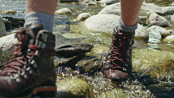 Young man crossing the stream. Walking on rocks