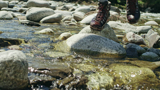 istock Backpacker crossing the stream. Close up on hiking boots 1131987113