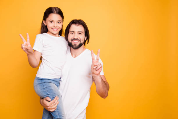 Portrait of her she his he nice cute sweet lovely attractive cheerful people dad holding in hands pre-teen girl showing v-sign isolated over shine vivid pastel yellow background Portrait of her she his he nice cute sweet lovely attractive cheerful people dad holding in hands pre-teen girl showing v-sign isolated over shine vivid pastel yellow background. fashionable dad stock pictures, royalty-free photos & images