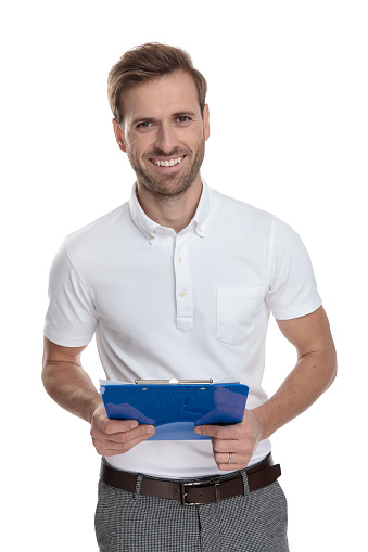 happy young student holding notepad while standing on white background
