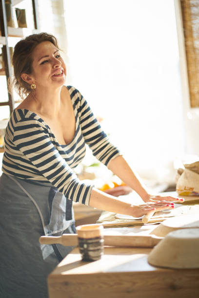 istock Beautiful happy  woman making ceramic ware in workplace, laughing, smiling in sun light. Concept for woman in freelance, business, hobby 1131989011