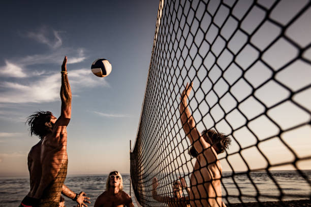 young man blocking his friend while playing beach volleyball in summer day. - volleyball beach volleyball beach sport imagens e fotografias de stock