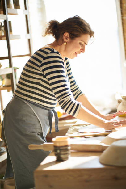istock Beautiful happy  woman making ceramic ware in workplace, laughing, smiling in sun light. Concept for woman in freelance, business, hobby 1131989103