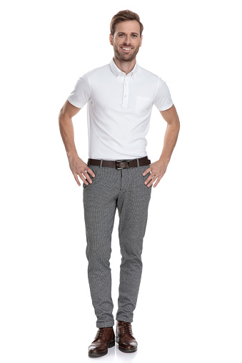 happy young smart casual man with hands on waist standing on white background