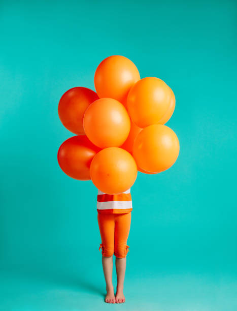 istock Girl holding orange balloons in front 1131989400