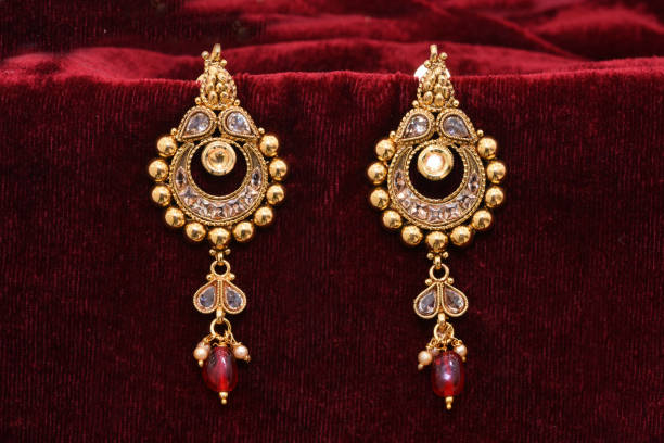 istock Fancy Designer golden earrings closeup macro image on red background 1131990358