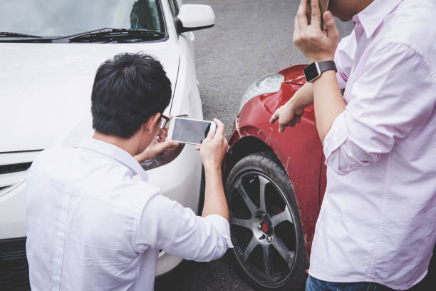 two drivers man arguing after a car traffic accident collision and making phone call to insurance agent and take a photo, traffic accident and insurance concept - personal land vehicle fotos imagens e fotografias de stock