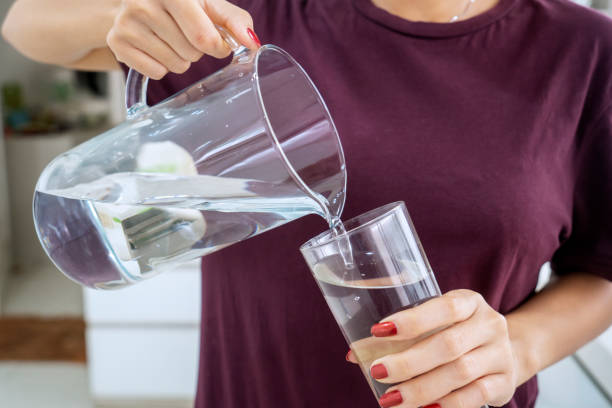 istock Unknown woman pouring water into the glass 1131997160