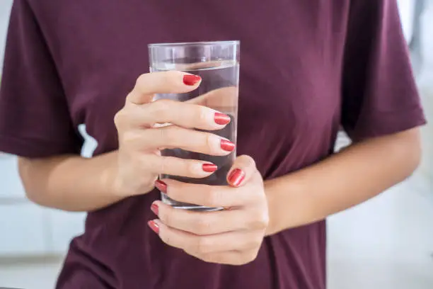 Close up of young woman hands holding a glass of fresh water