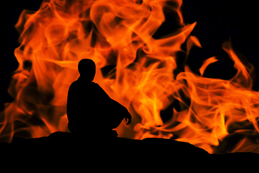 silhouette of a monk, meditating on fire background