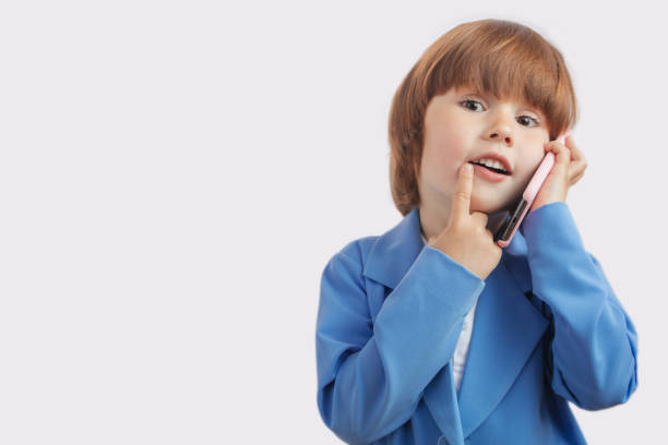 reicher junge mit einem finger auf den lippen. gorgeouse-junge hat ein geheimes gespräch - telephone child isolated on white elegance stock-fotos und bilder