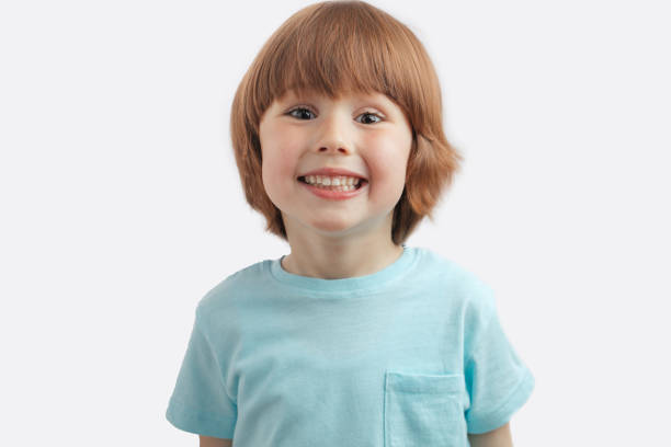 niño bastante pelirrojo mostrando sus dientes blancos - t shirt child white portrait fotografías e imágenes de stock