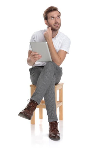 istock curious seated man holding tablet looks up at something 1131998713