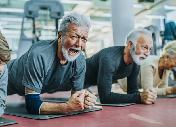 istock Senior man shouting while making an effort to stay in plank position on exercise class. 1131999209