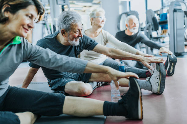 gruppe von senioren, die ihre beine in einem fitnessstudio strecken. - senior adult healthy lifestyle athleticism lifestyles stock-fotos und bilder