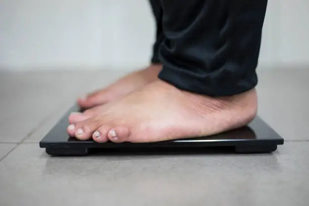 Close up of young male bare feet standing on the scale while checking weight