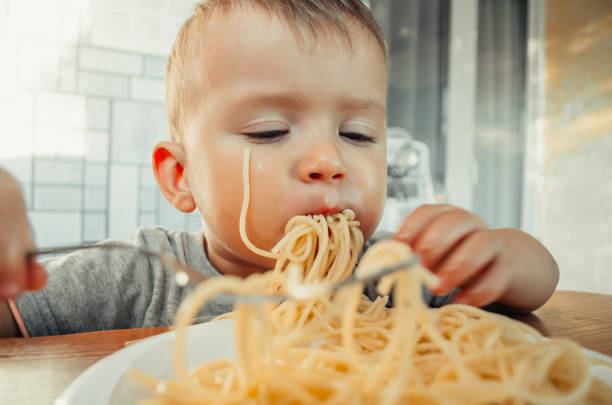 istock Baby in the kitchen eagerly eating pasta 1132000999