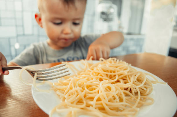 istock Baby in the kitchen eagerly eating pasta 1132001042