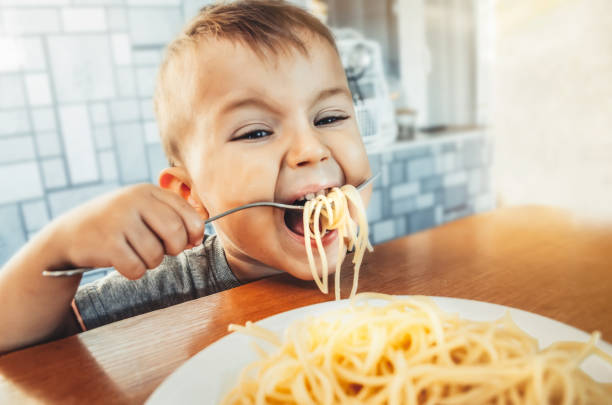 istock Baby in the kitchen eagerly eating pasta 1132001606