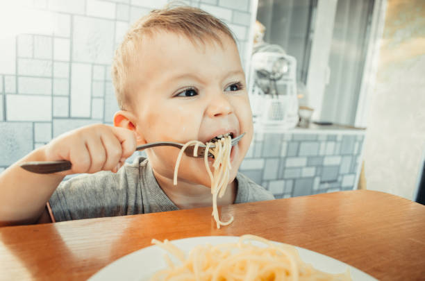 istock Baby in the kitchen eagerly eating pasta 1132001676