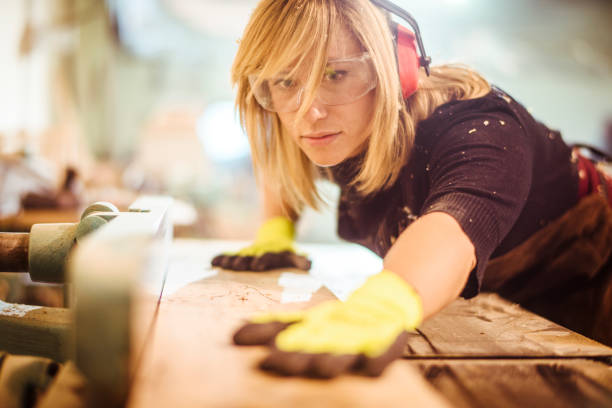 istock Female carpenter pushing a plank to cut it using a saw guide 1132001940