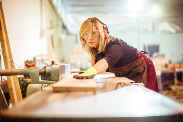 istock Female woodworker aligning a plank on a saw guide on a work bench before cutting it 1132002070