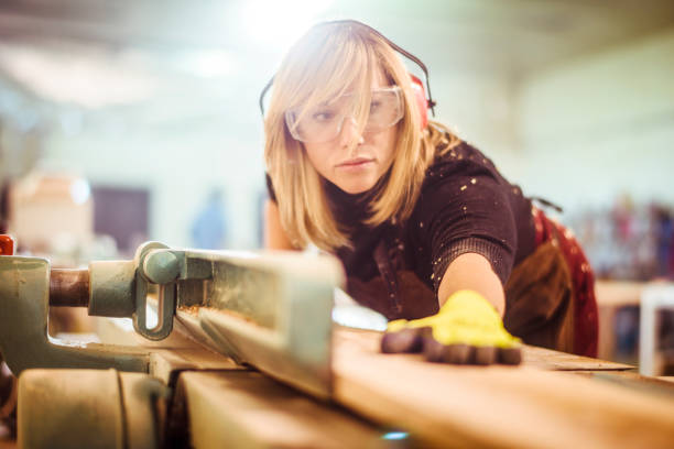 istock Girl carpenter adjusting a wooden plank angle on a saw guide before cutting it 1132002072