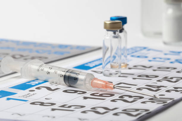 Syringe and Several Vials Vaccine on a Calendar stock photo