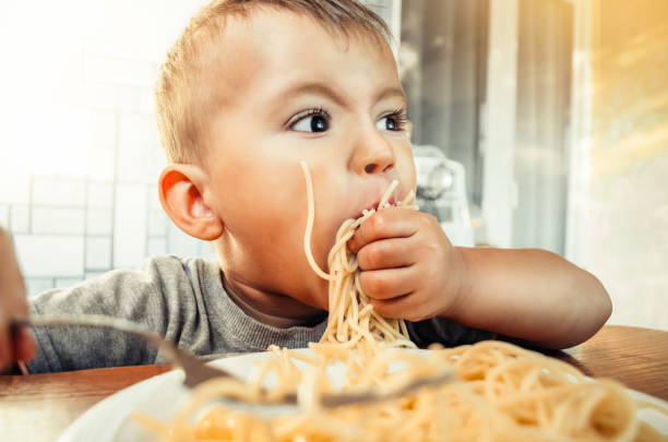 istock Baby in the kitchen eagerly eating pasta 1132002350