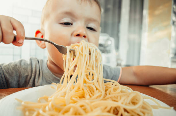 istock Baby in the kitchen eagerly eating pasta 1132002399