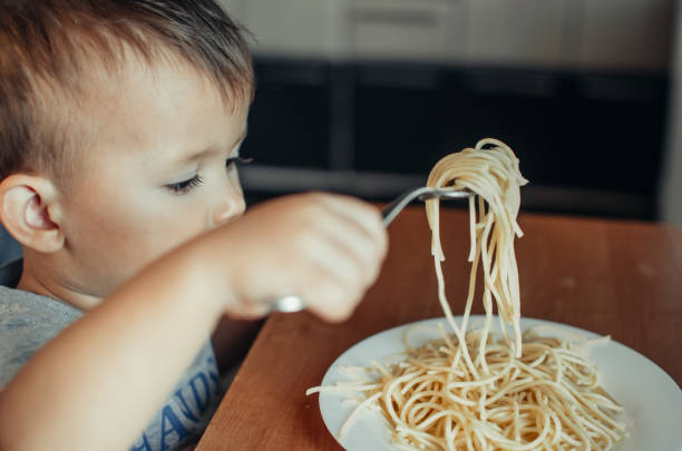istock Baby in the kitchen eagerly eating pasta 1132002542