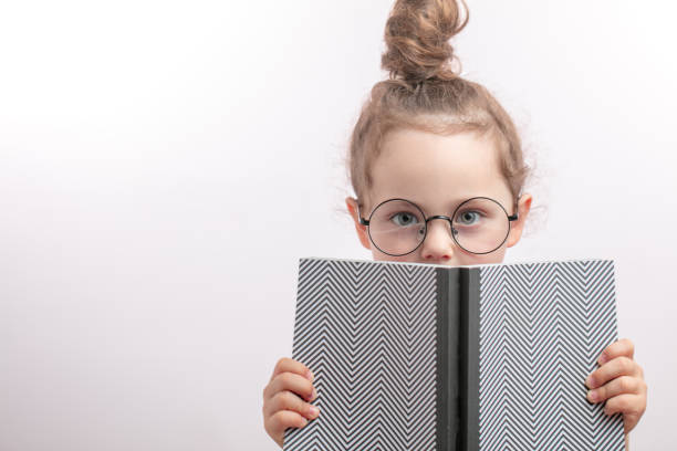 istock little pleasant girl hiding behind the book 1132003088