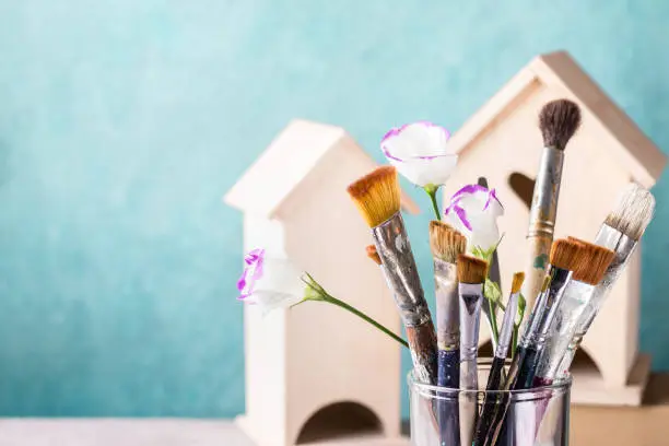 Photo of Art Creativity Concept. Brush Set, flowers and wooden house for decoration