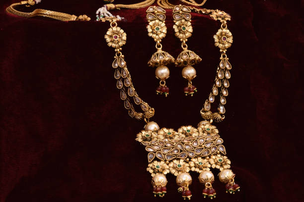 istock Fancy designer golden neckset closeup macro image on red background. 1132003810