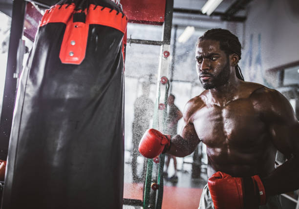 istock Determined black boxer punching a bag on sports training in a gym. 1132003841