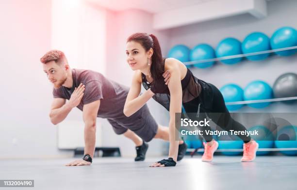 Pretty Young Couple Doing Exercises Together In The Light Gym Stock Photo - Download Image Now