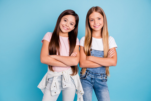 Portrait of nice-looking cute lovely sweet adorable well-groomed attractive cheerful cheery straight-haired brunette blonde girls siblings folded arms isolated over blue pastel background.