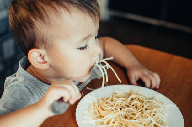 istock Baby in the kitchen eagerly eating pasta 1132004318